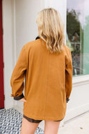 Person wearing a camel jacket standing in front of a door.