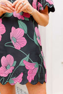 Close-up of a person wearing a dress with pink floral pattern on a plain background