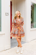 Woman in a patterned dress standing outside a house