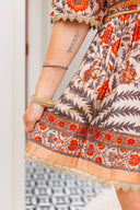 Close-up of a person wearing a patterned dress with orange and beige colors.