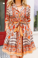 Woman wearing a patterned dress with a belt in an outdoor setting