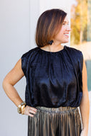 Black satin sleeveless top and pleated palazzo pants.