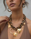 Woman wearing a gold charm necklace with leopard print scarf intertwined.