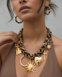 Woman wearing a gold charm necklace with leopard print scarf intertwined.