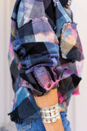 Multicolored plaid shirt with frayed edges and a person wearing it.