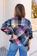 Person wearing a colorful plaid shirt with a blurred background