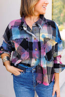 Person wearing a colorful plaid shirt and blue jeans with a blurred background