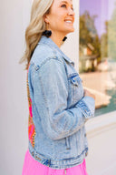 Woman wearing a denim jacket and pink skirt outdoors