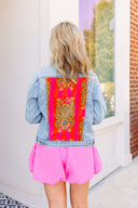 Person wearing a denim jacket with a colorful back panel in an outdoor setting