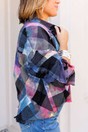 Person wearing a colorful plaid shirt with a blurred background