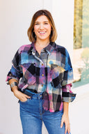 Woman in neon flannel with brass buttons standing outside boutique.