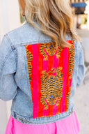 Denim jacket with a colorful tiger pattern on the back, worn by a person.