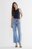 Woman wearing a black sleeveless top and light blue jeans on a white background