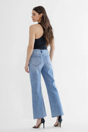 Woman wearing light blue jeans and a black top on a white background