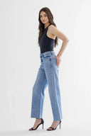 Woman wearing a black sleeveless top and light blue jeans on a white background