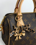 Bag charm adorned with leopard bow and gold charms. 