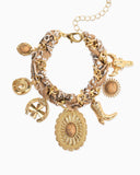 Gold charm bracelet with various charms intertwined with a paisley scarf.